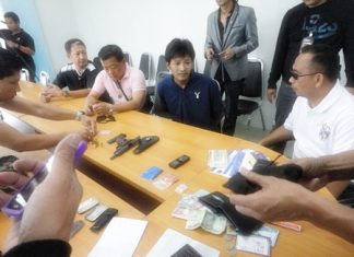 Saksit Suwadit (seated center) is brought in for questioning after police nailed him in a sting operation.